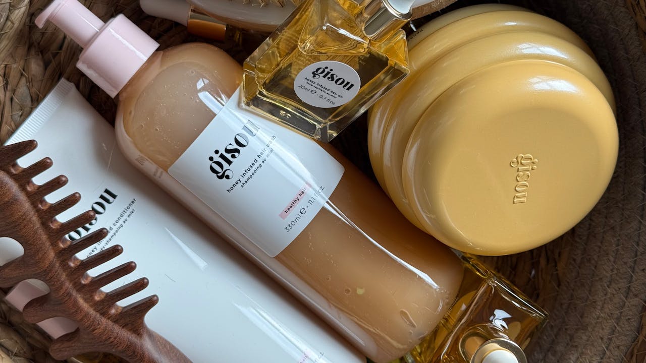 hero-img-01 A stylish arrangement of Gisou hair products in a basket with natural aesthetics.